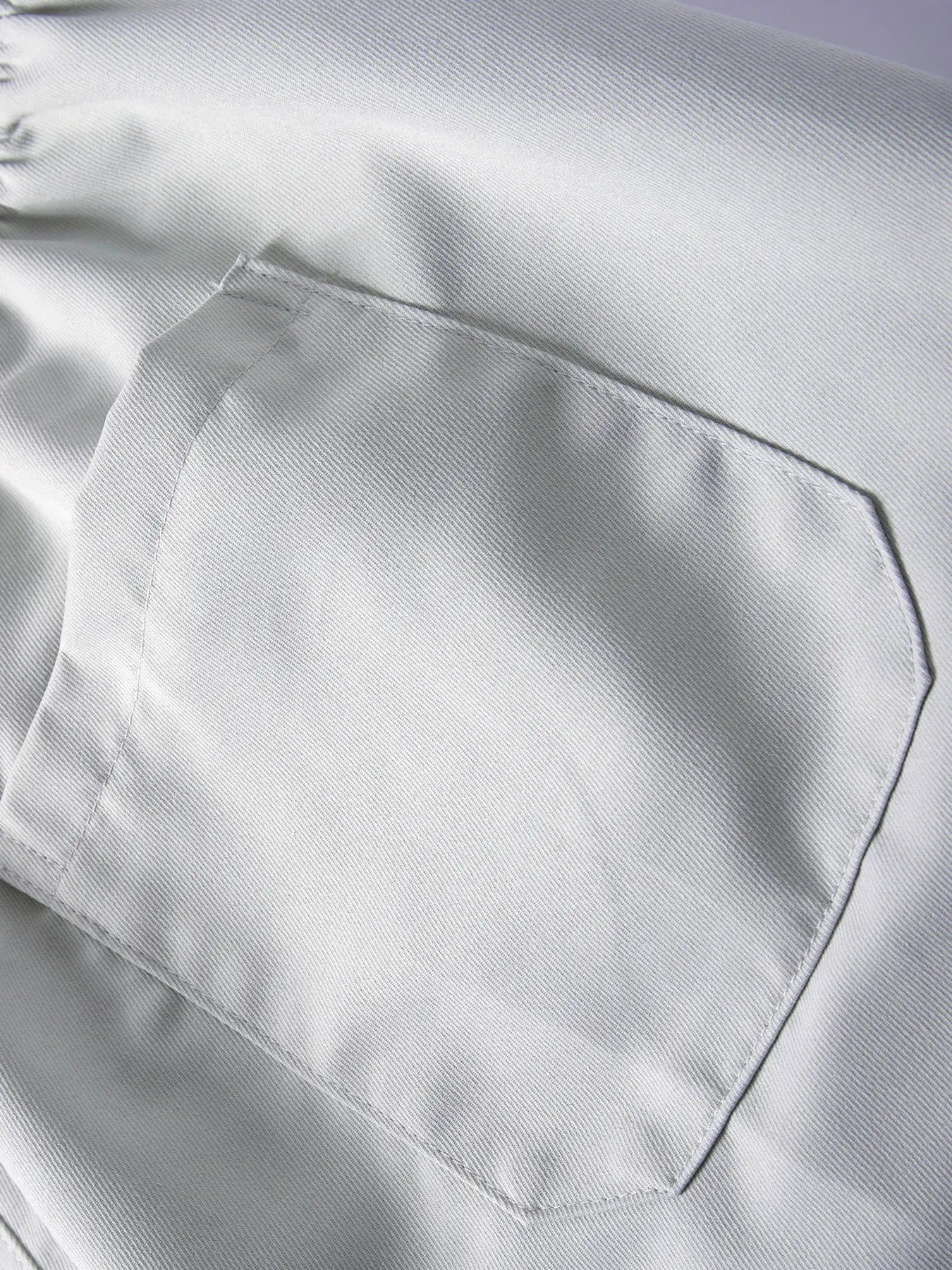Men's light gray cargo pants close-up of front pocket and visible stitching