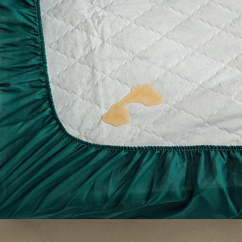 Waterproof quilted mattress protector with teal elastic edge; stained quilted top
