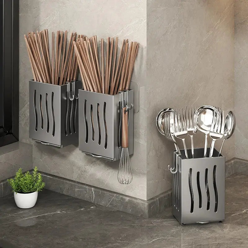 Gray metal chopstick storage boxes (two) with drainage holes on the wall, plus a floor utensil caddy holding spoons.