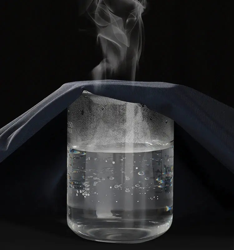 Beaker with rising steam partially covered by blue fabric against a dark background.