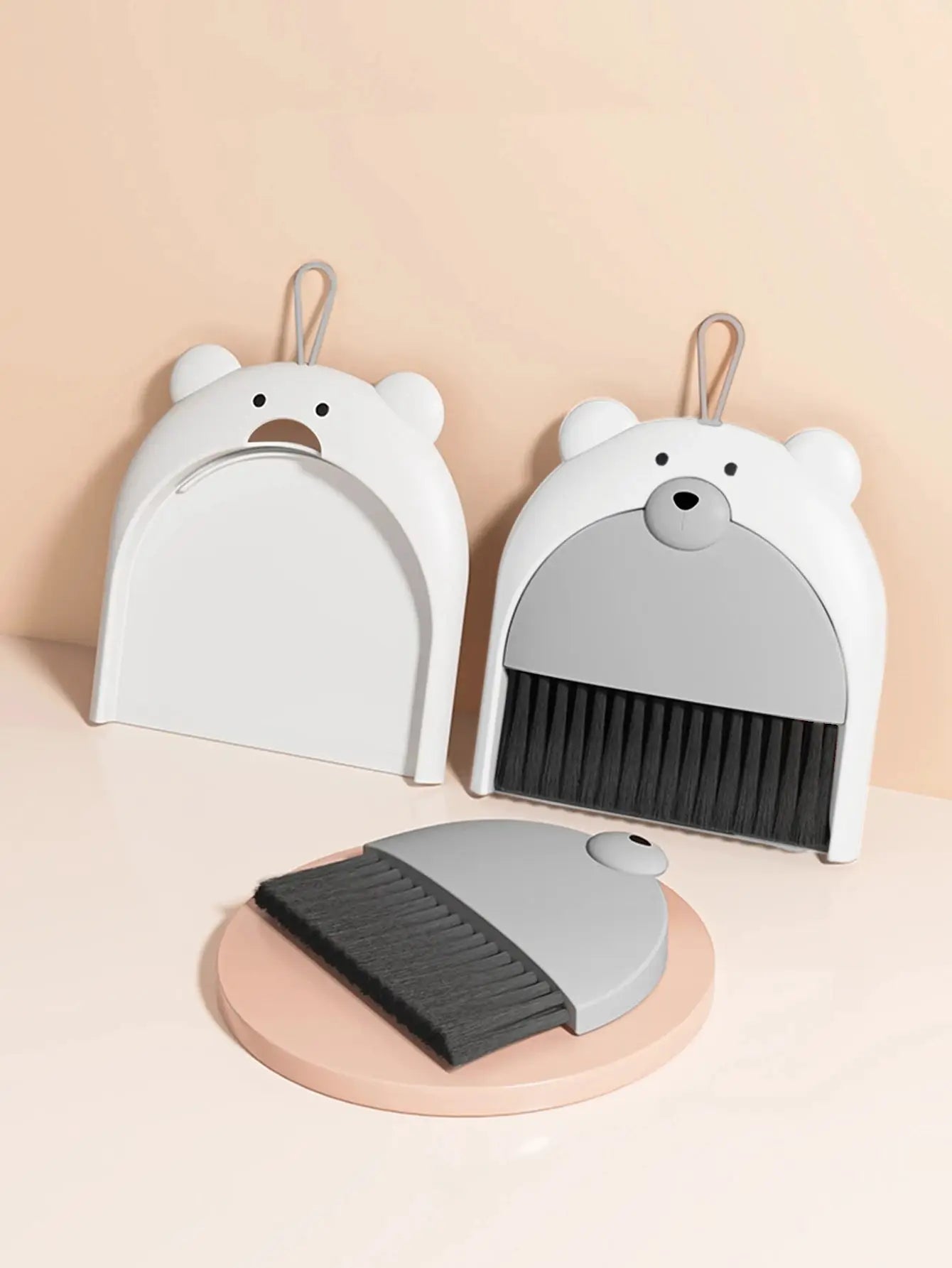 Two bear-shaped broom and dustpan sets by Simples Market, white with gray accents and black bristles