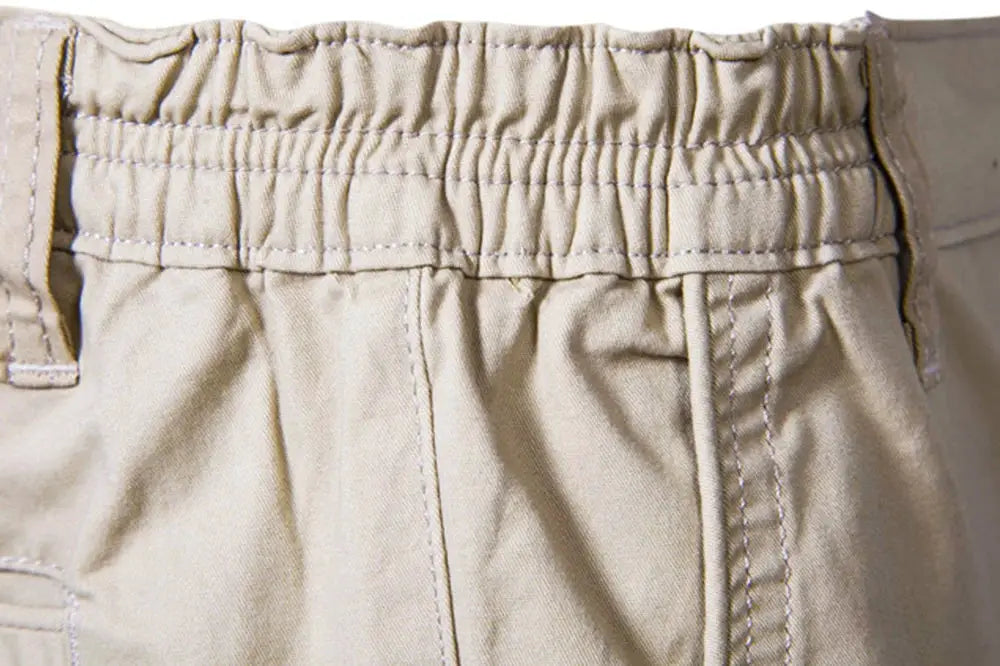 Men's beige 100% cotton shorts with elastic waistband and belt loops, close-up waistband detail.