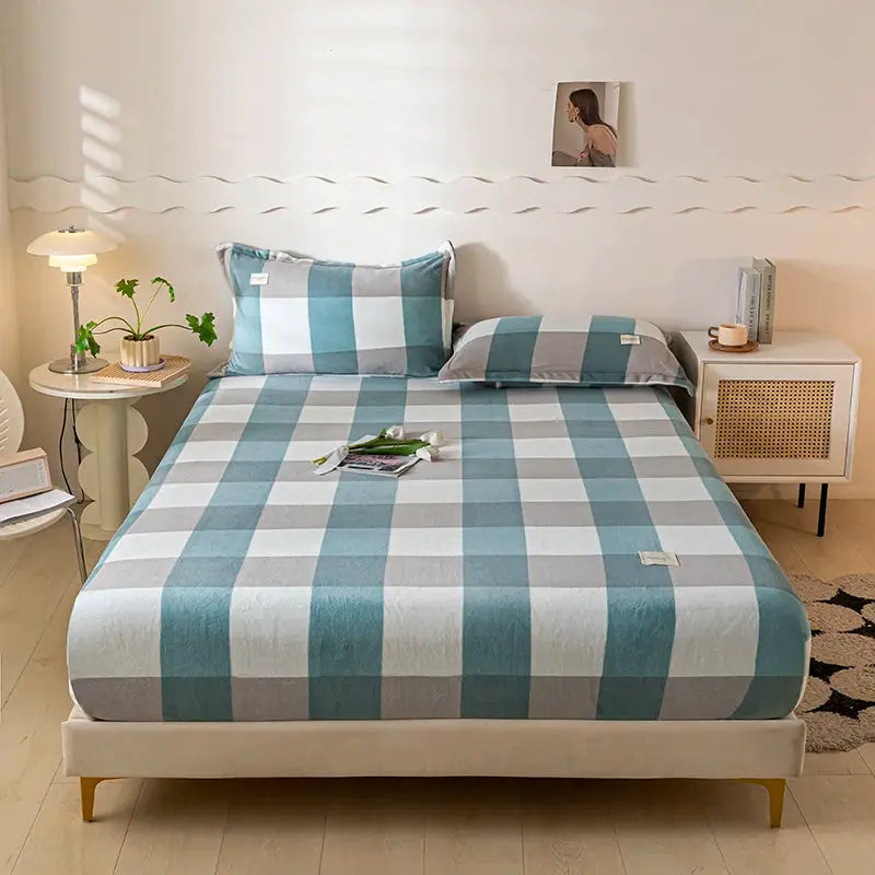 Velvet thermal mattress cover with teal and gray plaid plush sheets on a queen bed with two pillows by Simples Market