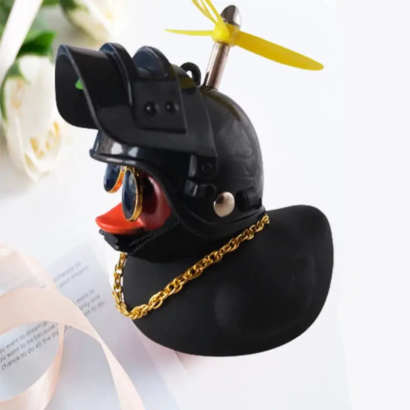 Rubber duck car ornament with a black helmet, yellow propeller, and gold chain necklace