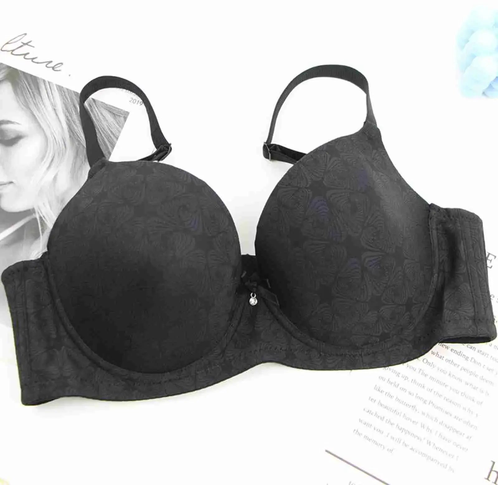 Black bra with floral embossed cups, padded underwire, adjustable straps, and center bow.