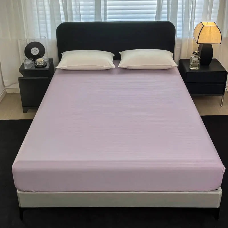 Fitted bed sheet with elastic band in lavender solid color on a bed