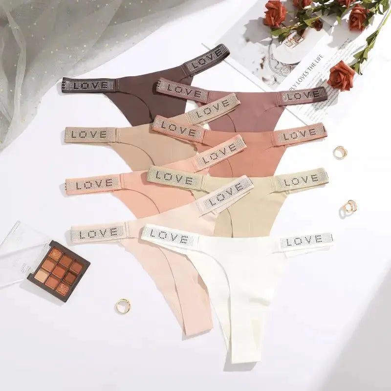 7-piece thong set with rhinestone LOVE waistband in nude, beige, pink, and white shades; low-rise, soft fabric