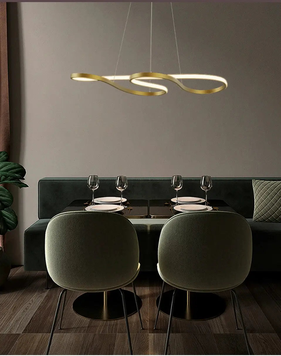Gold-tone modern kitchen island pendant light with looping LED rings over a dining table