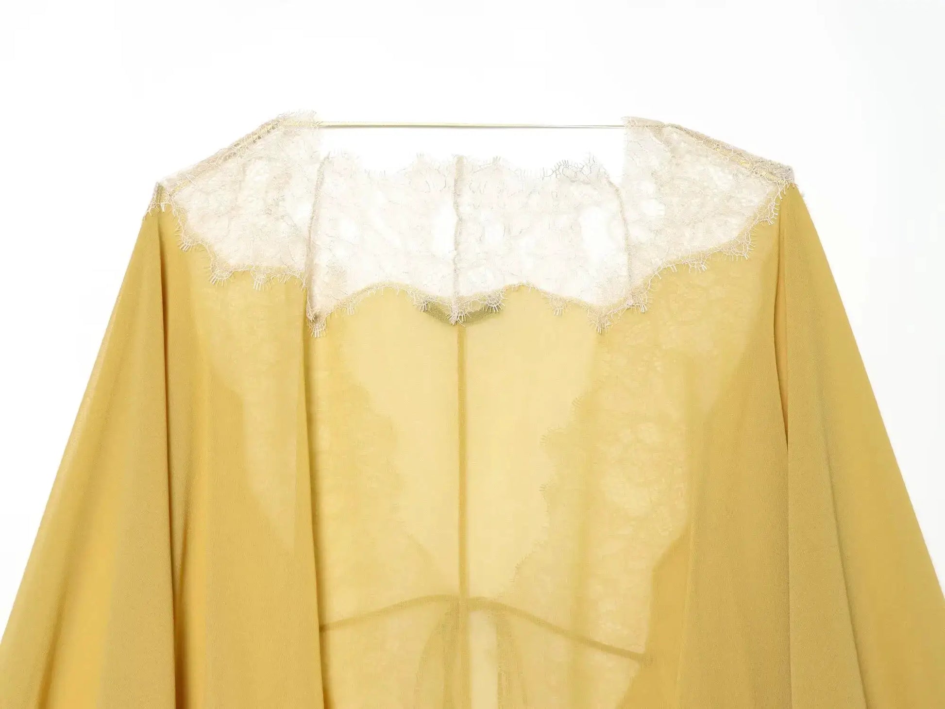 Lace-trim mustard-yellow sheer blouse with lantern sleeves on a hanger