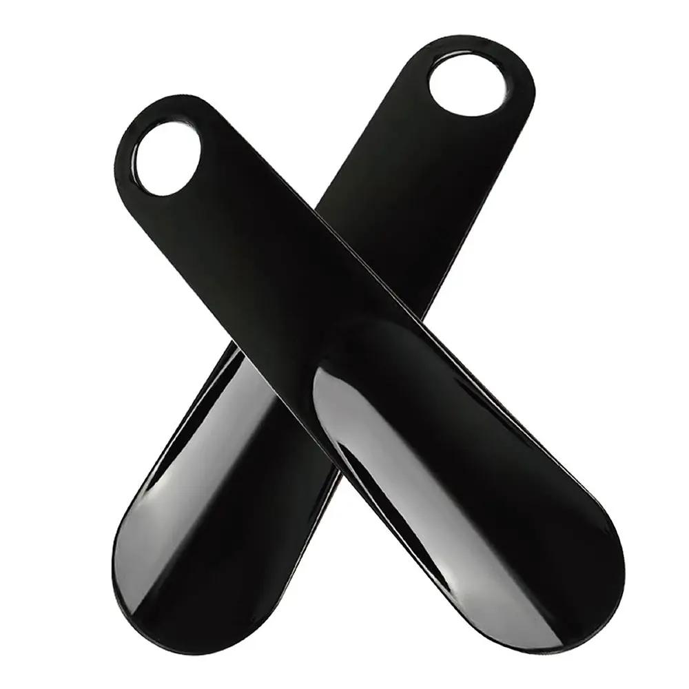 Two black plastic spoon-shaped shoe horns crossed in an X pattern