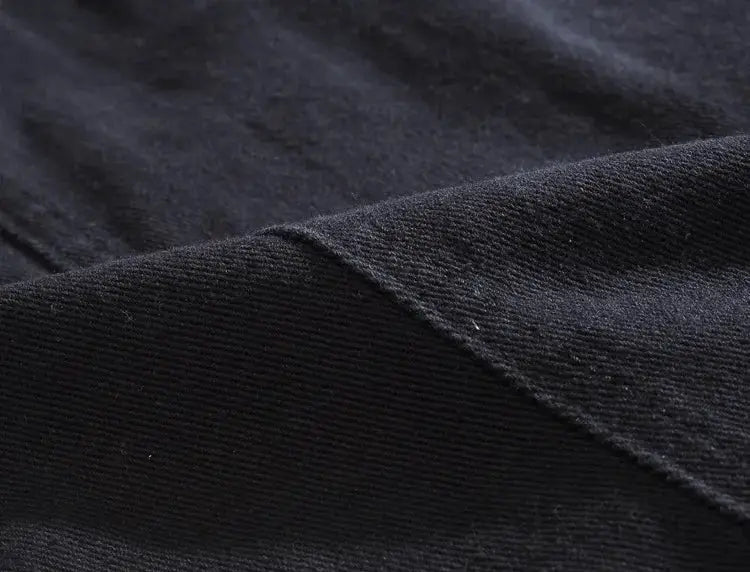 Denim vest fabric in black; close-up shows tight twill weave and rugged texture.