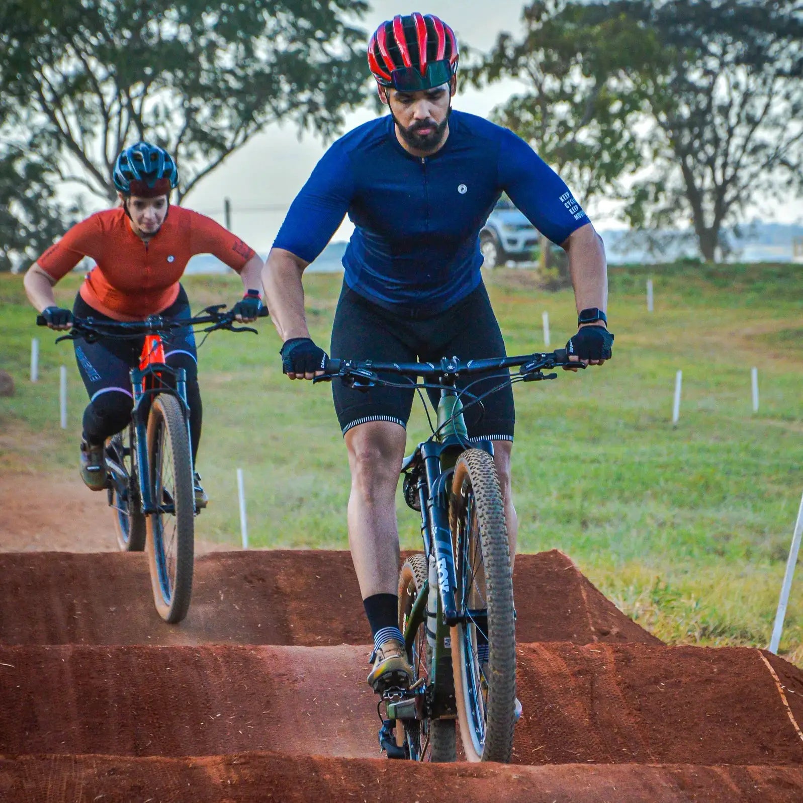 DAREVIE cycling jersey, blue long-sleeve SPF 50+ training maillot worn by two cyclists on a dirt track