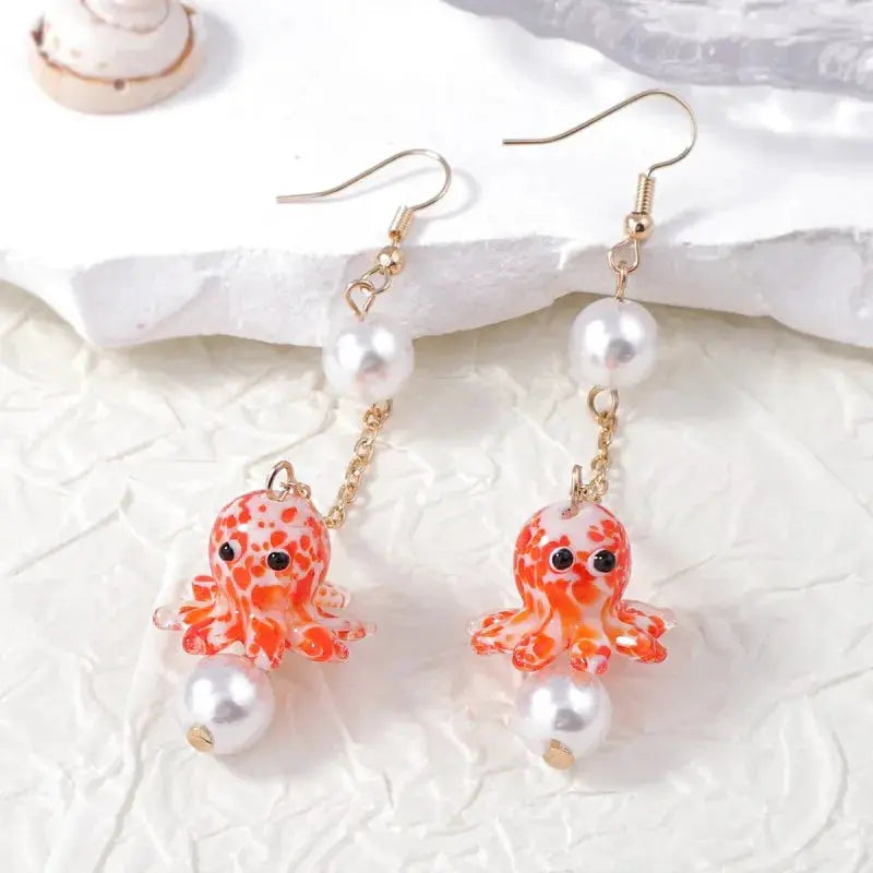Long-drop octopus earrings with orange glass octopus charms, pearl beads, and gold-tone chains