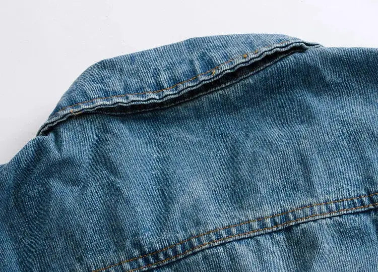 Men's light-blue denim jacket fabric close-up with visible orange stitching