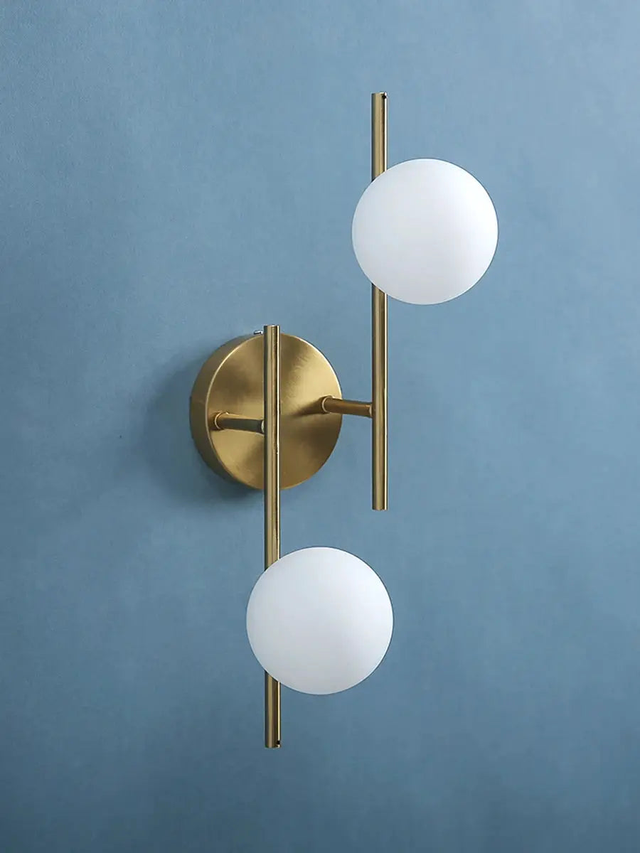 Modern LED wall lamp set in gold with two milky glass spheres on brass vertical rods.