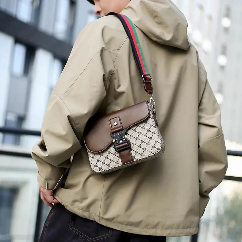 Men's crossbody bag with beige jacquard pattern, brown leather flap, and green-red-green shoulder strap