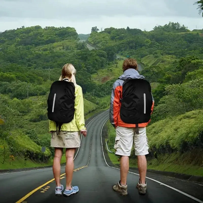 Couple standing on a road with backpacks, featuring a reflective waterproof backpack rain cover for safety in unpredictable weather.
