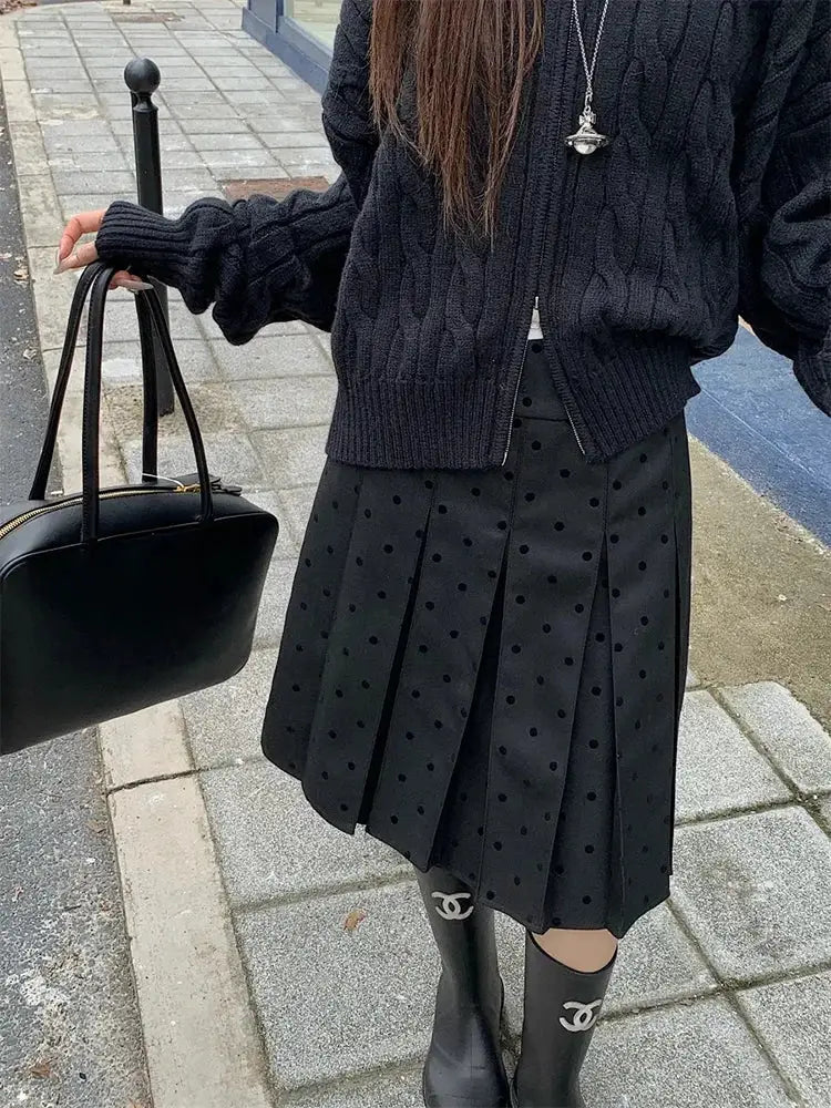 Polka dot pleated black high-waist A-line skirt with Chanel boots and a black handbag