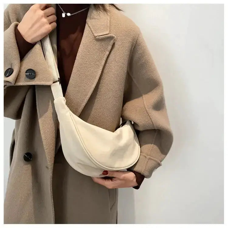 Simples Market nylon dumpling bag, cream crescent crossbody worn over a beige coat.