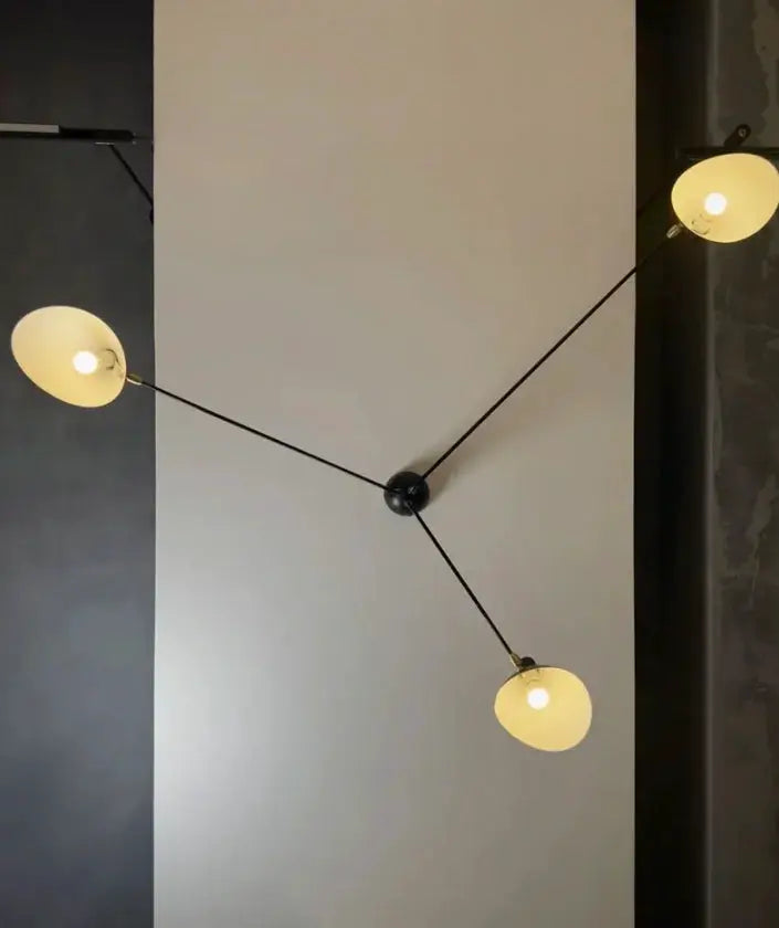 Modern spider pendant light with three black arms and warm globe bulbs by Simples Market for living room
