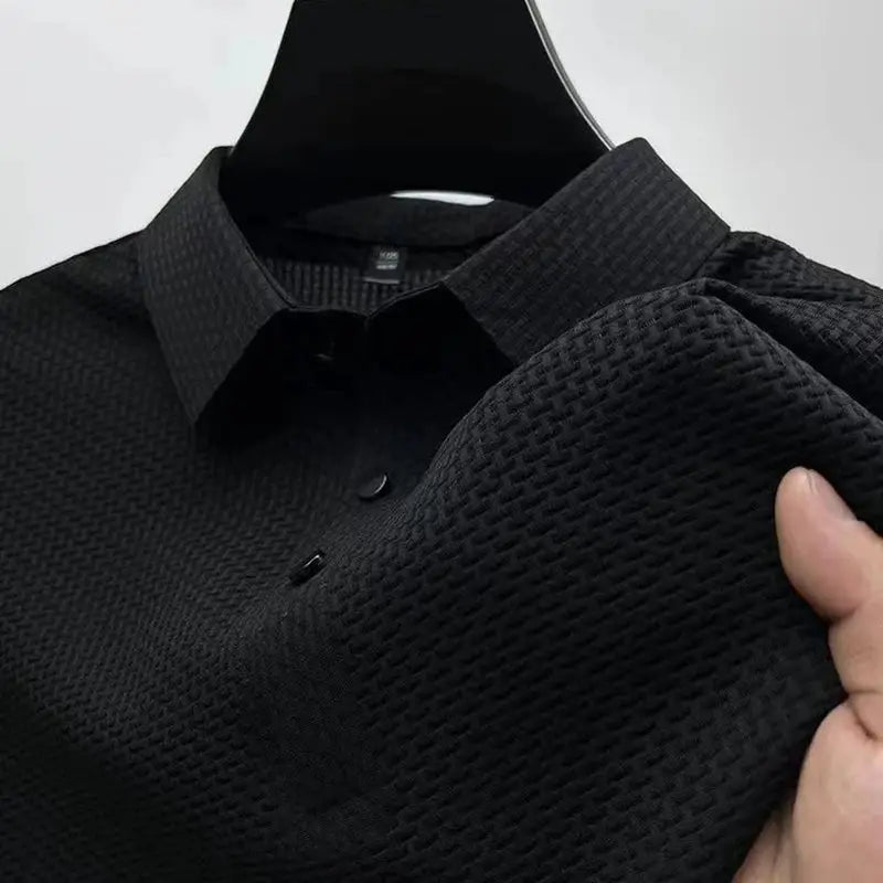 Men's black textured polo shirt with short sleeves and button placket.
