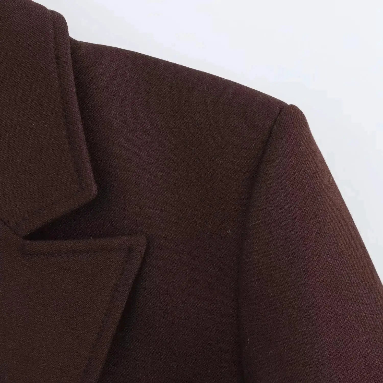 Blazer brown close-up showing lapel, pocket and textured fabric.
