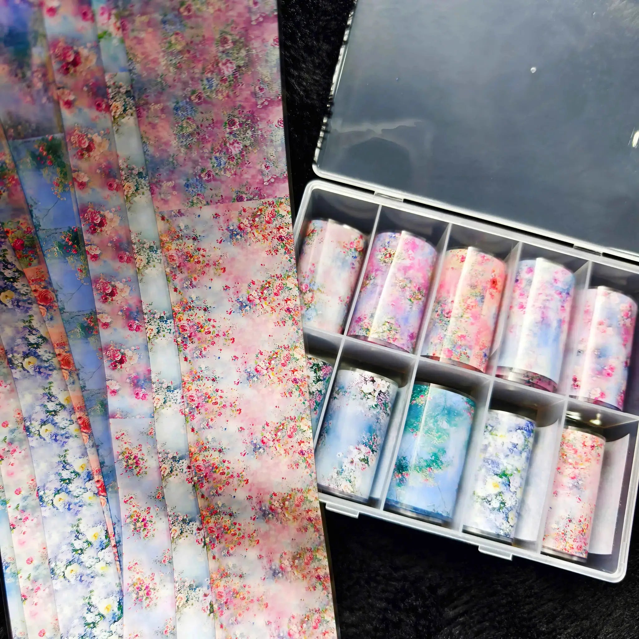 Nail foil sheets with pastel floral designs, assorted patterns, displayed in a rack for nail art.