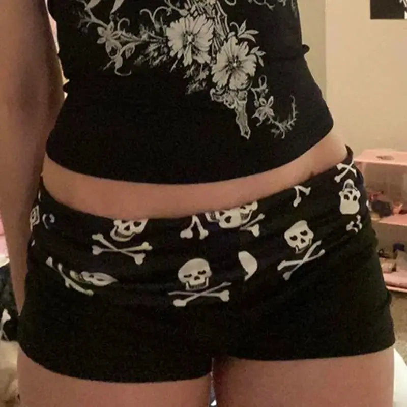 Skull-print shorts by Simples Market, black with white skulls, low-rise casual streetwear for women.