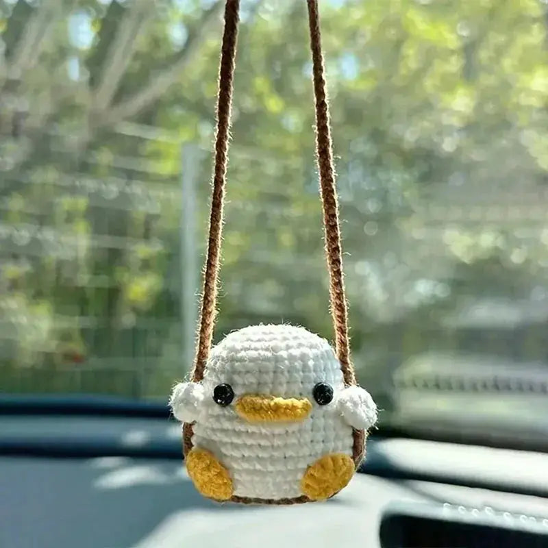 Crochet duck car interior pendant with white body, yellow beak and feet, brown strap