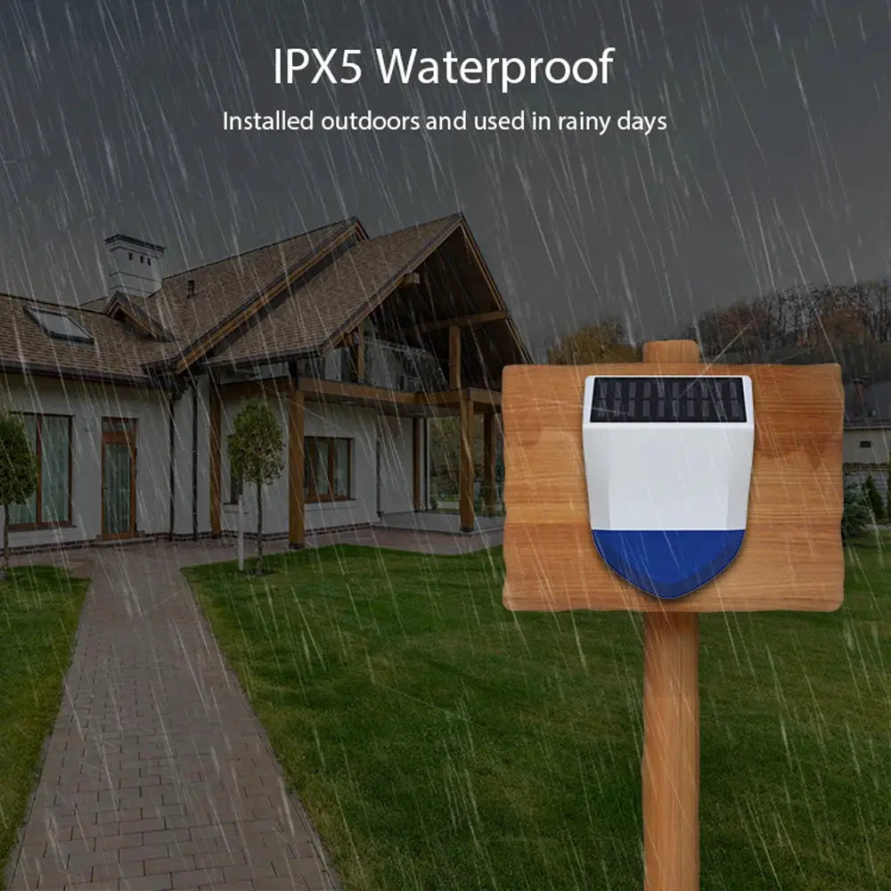 Outdoor siren alarm with solar panel mounted on a wooden post, IPX5 waterproof for rainy days.