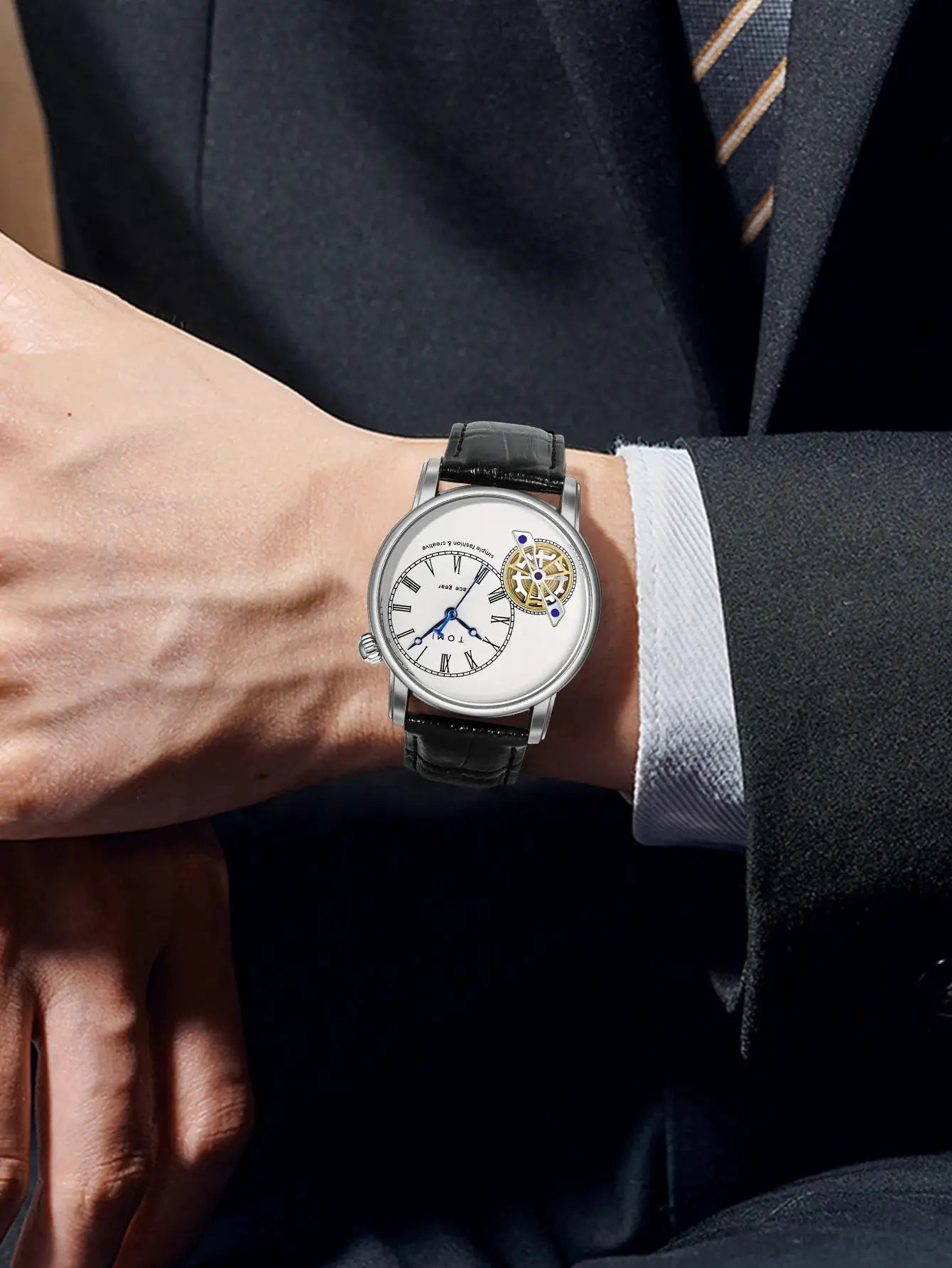 TOMI men's quartz watch on wrist; white dial with Roman numerals, blue hands, visible gear, black leather strap