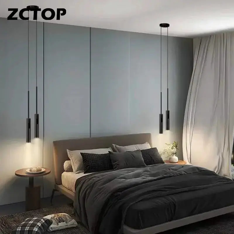 Minimalist LED hanging pendant light set by Simples Market; four black cylindrical pendants over a bed.