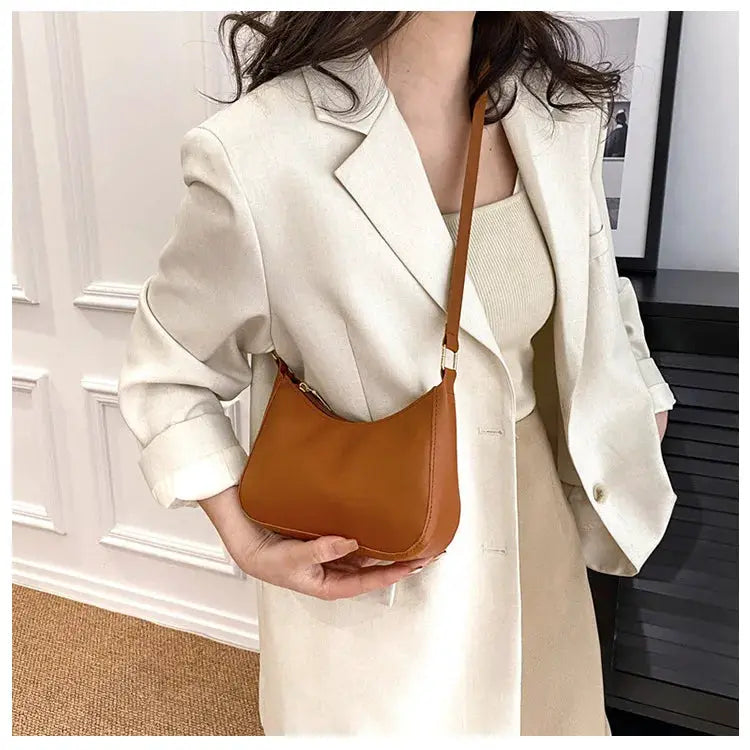 Small tan leather handbag with a compact square silhouette and single shoulder strap