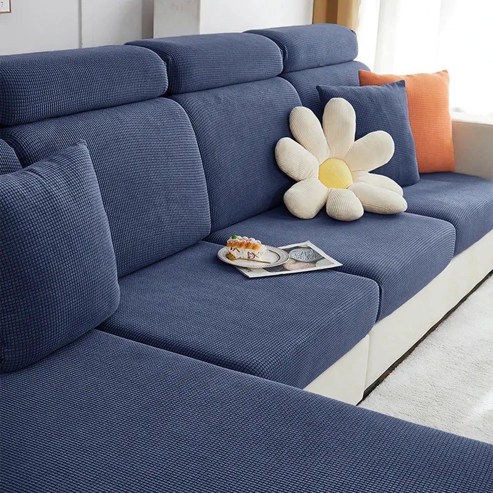 Blue jacquard polar-fleece sofa cover on a sectional couch with cushions and a daisy pillow