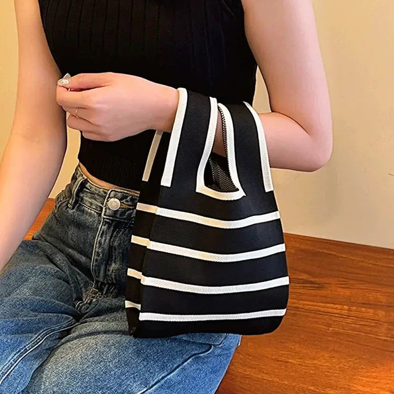 Mini striped handbag in black and white carried by a person wearing a black top and jeans.
