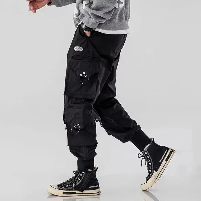 Cargo pants in black with multiple pockets and metal rings, streetwear style.