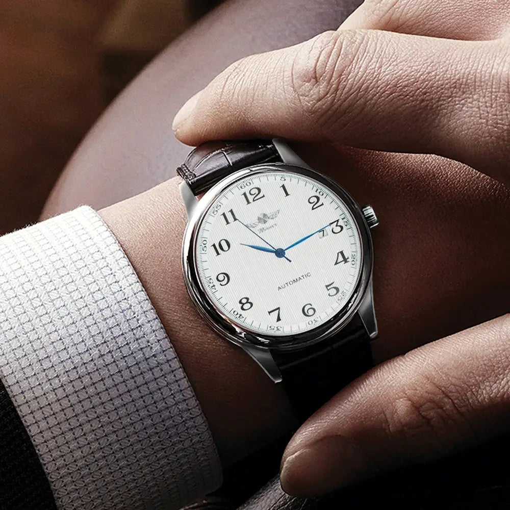 Men's automatic wristwatch with white dial, black numerals, blue hands, calendar window, steel case, leather strap
