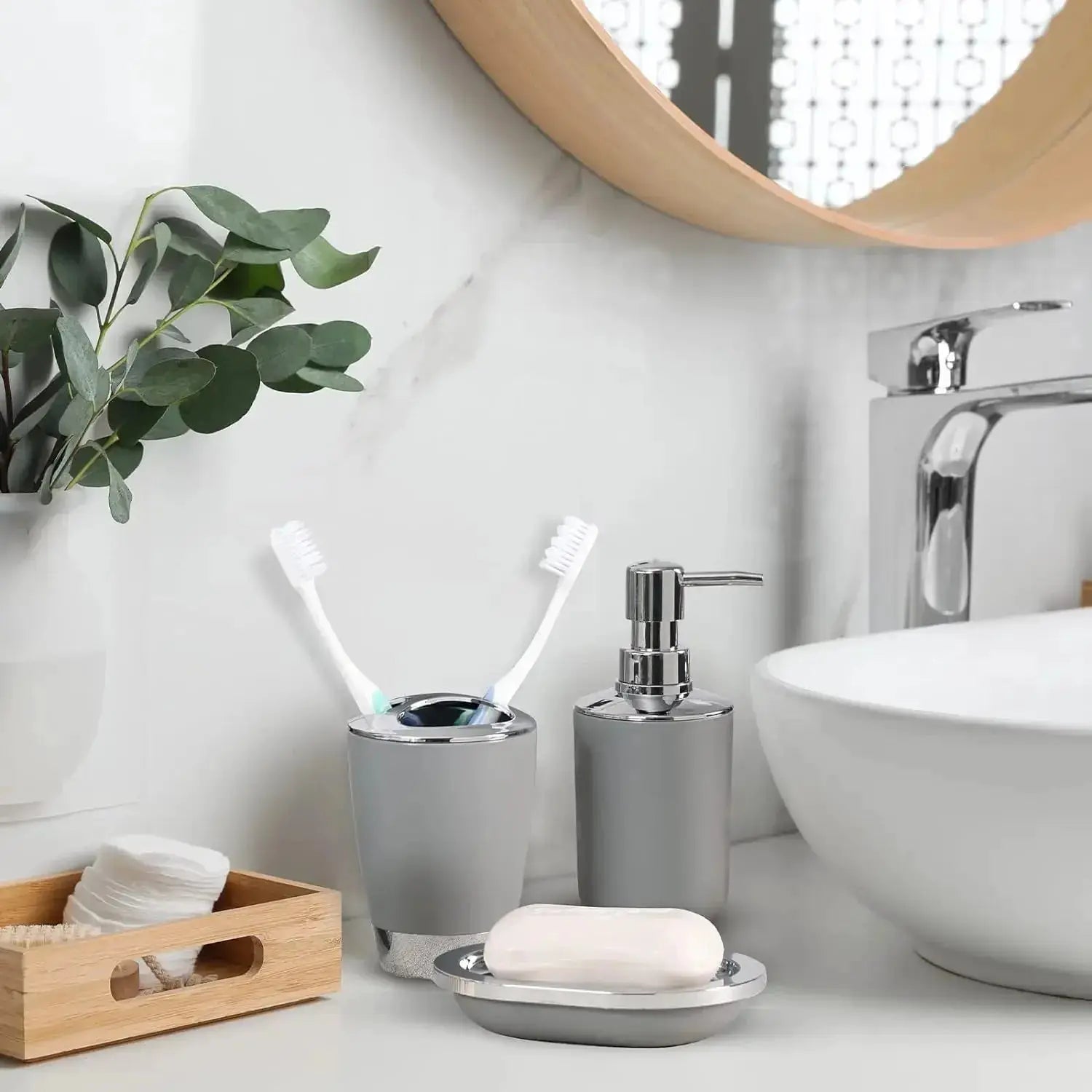 4-piece gray plastic bathroom set with toothbrush holder, toothbrush cup, soap dispenser and soap dish on a white counter
