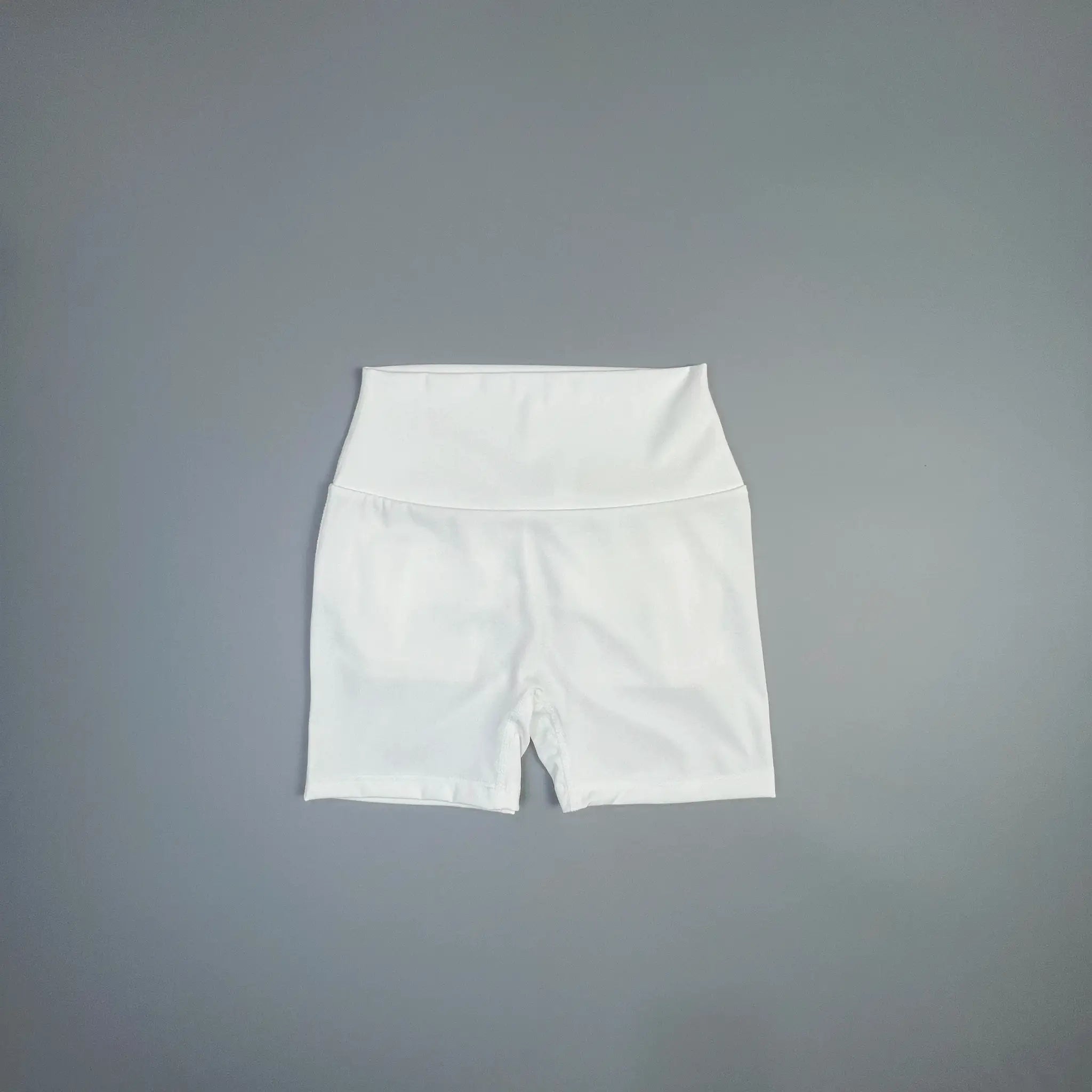 White high-waisted fitness shorts with wide waistband, laid flat on gray background