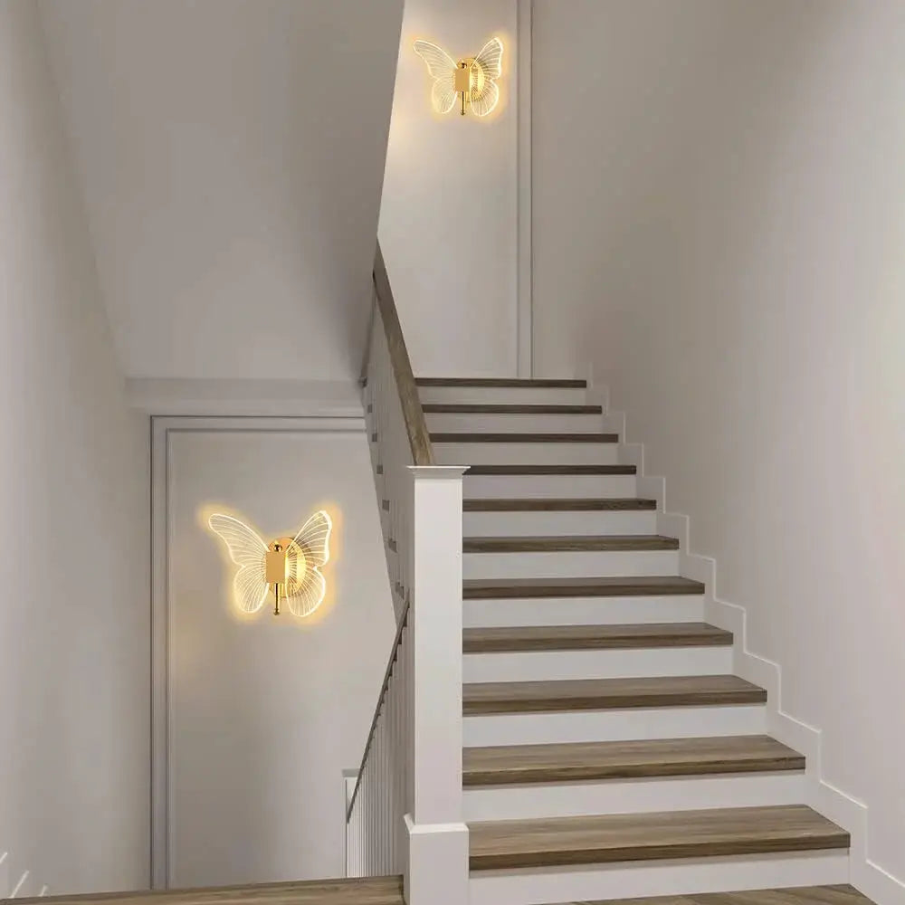 Butterfly LED wall lamps, 2 units, gold-tone metal with acrylic wings, warm lighting on staircase.