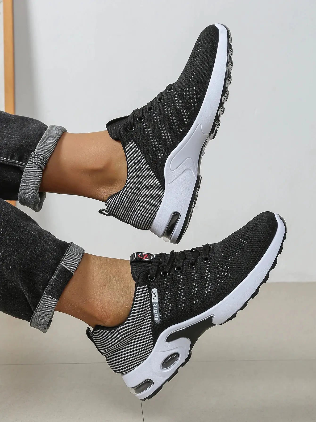 Pair of men's black knit running shoes with white sole and breathable lace-up