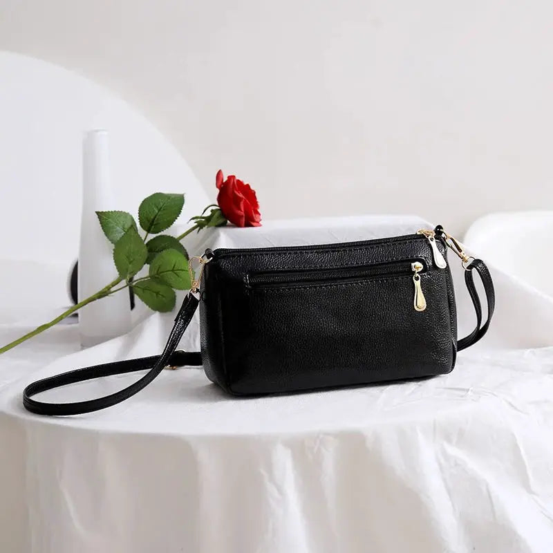 PU synthetic leather women's crossbody bag with alligator-textured black exterior, flap pocket and gold hardware.