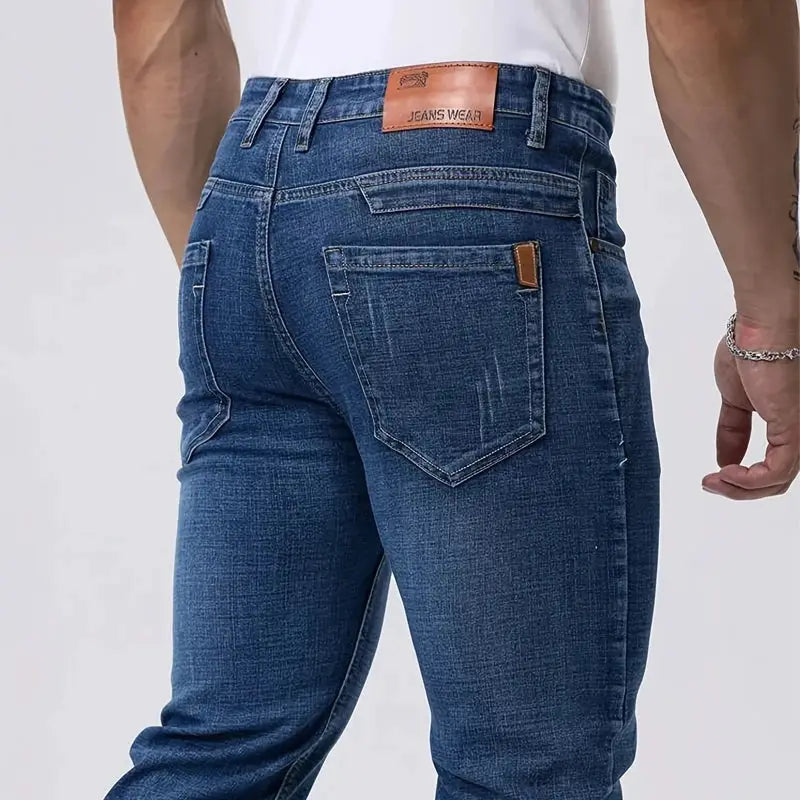 Men's blue stretch denim jeans; back view with brown leather patch and stitched back pockets