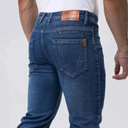 Men's blue denim jeans by Simples Market; straight, stretch denim with back pockets and leather patch.