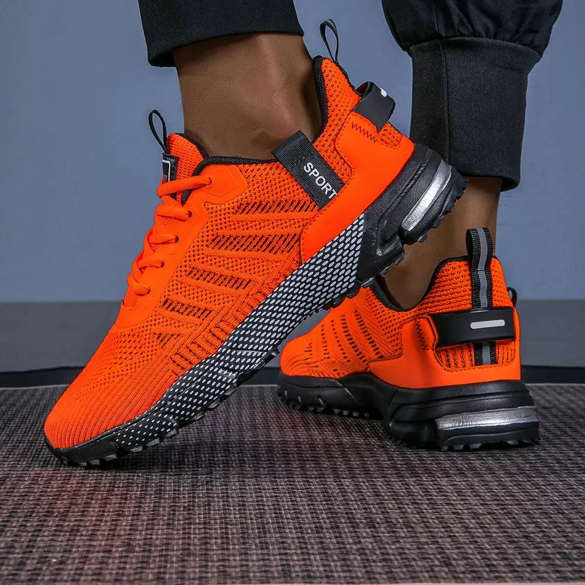 Pair of men's orange running shoes with breathable knit upper and black speckled sole, lace-up sneakers