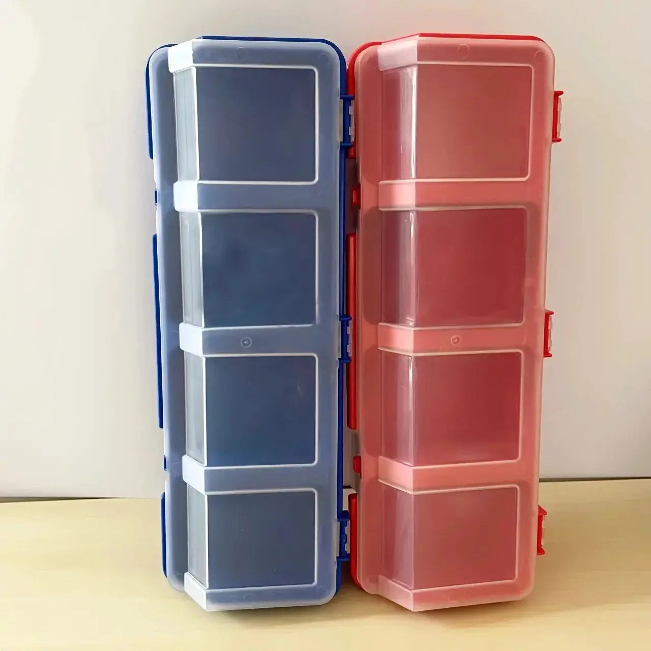 Two plastic multi-compartment organizer boxes in blue and pink with clear lids for screws and small parts.