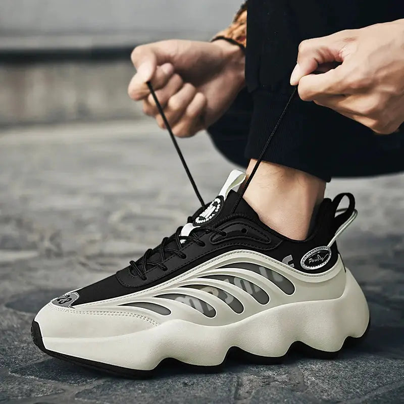 Men's sneakers in black with a cream chunky sole and wavy cutout side panels.