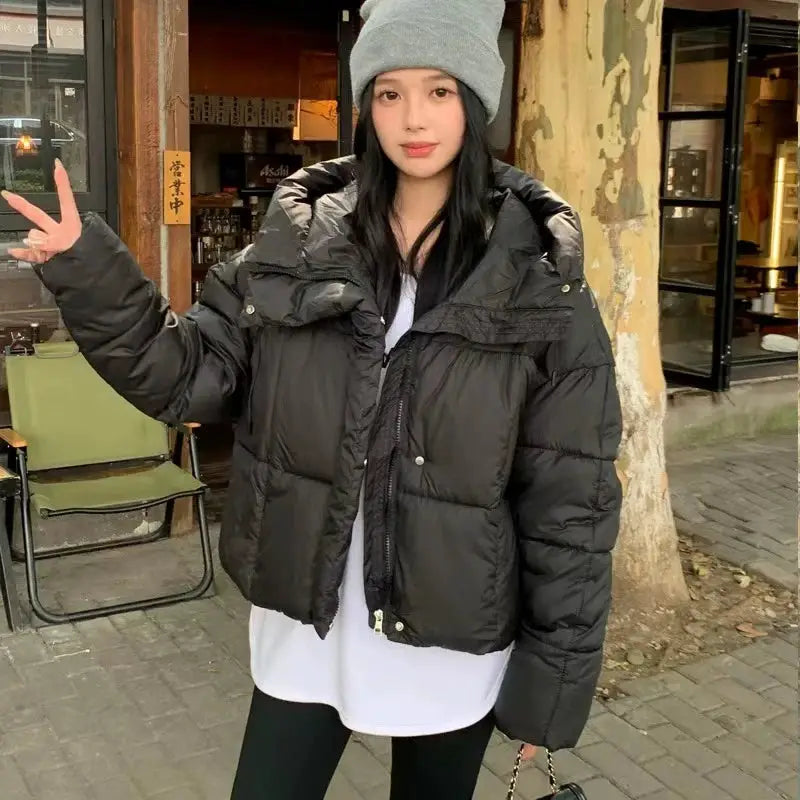 Women's black puffer jacket with oversized fit and front zipper, worn over a white shirt.