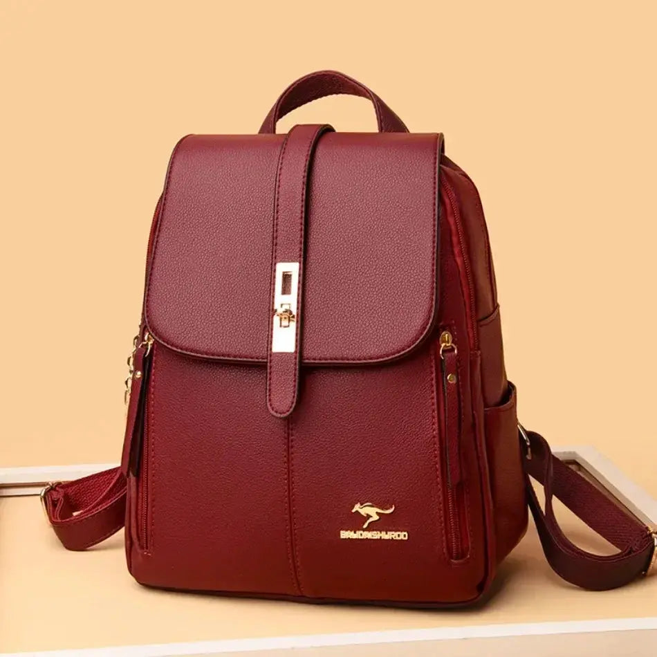 Women's burgundy leather backpack with large capacity, top handle, front flap strap, and gold hardware.