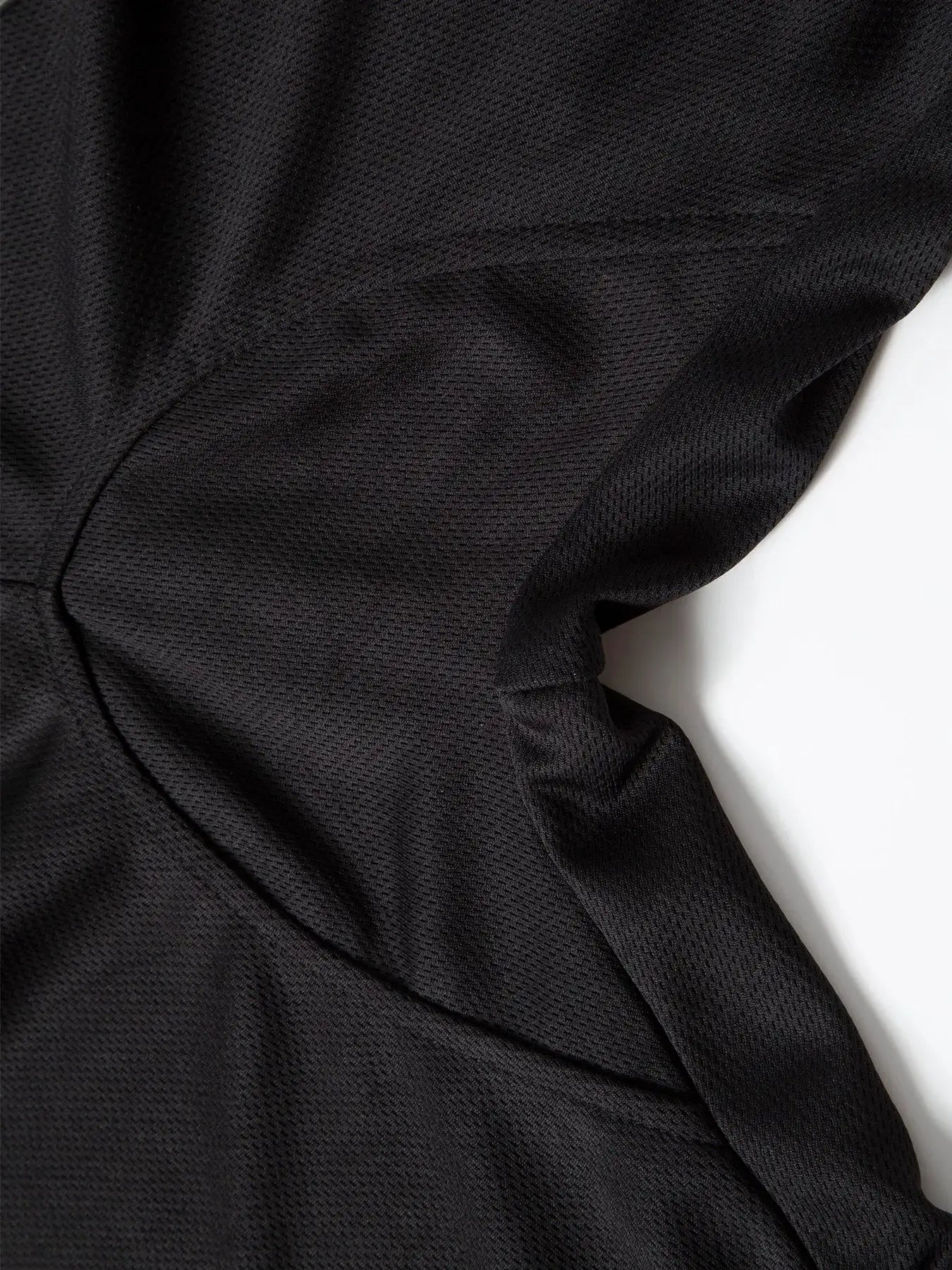 Men's black mesh sports shorts fabric close-up with stitching